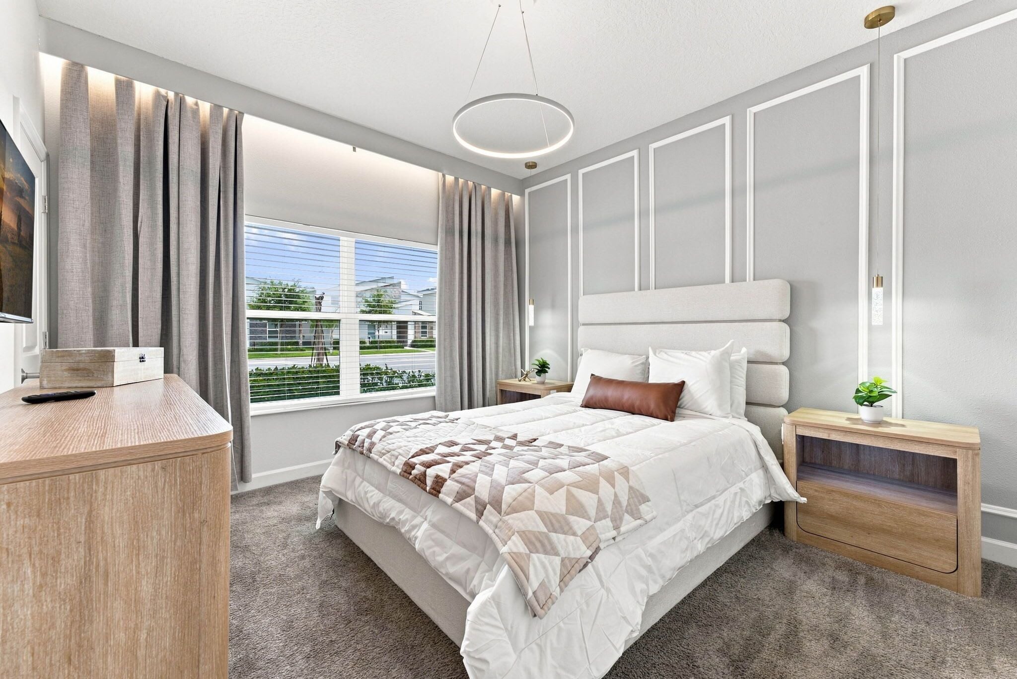 A modern bedroom with a large bed, a desk, and a window with curtains.