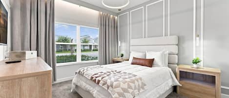 A modern bedroom with a large bed, a desk, and a window with curtains.