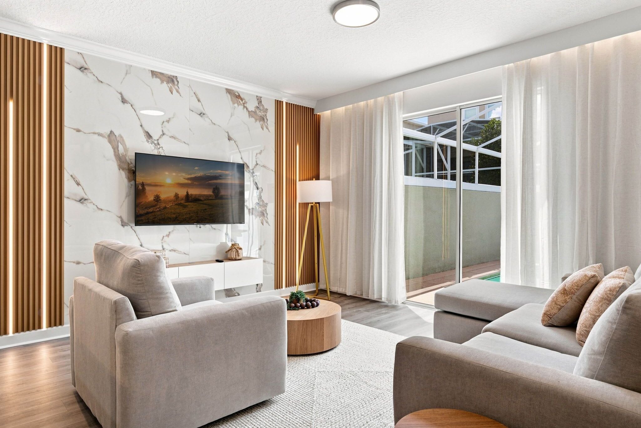 A modern living room with a flat-screen TV, two sofas, a coffee table, and a floor lamp.