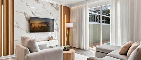 A modern living room with a flat-screen TV, two sofas, a coffee table, and a floor lamp.