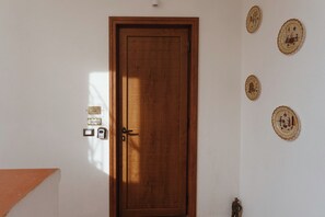 A wooden door with a keyhole and a handle, a light switch, and a P&P sign on the wall. - P&P Apartment (Forio)