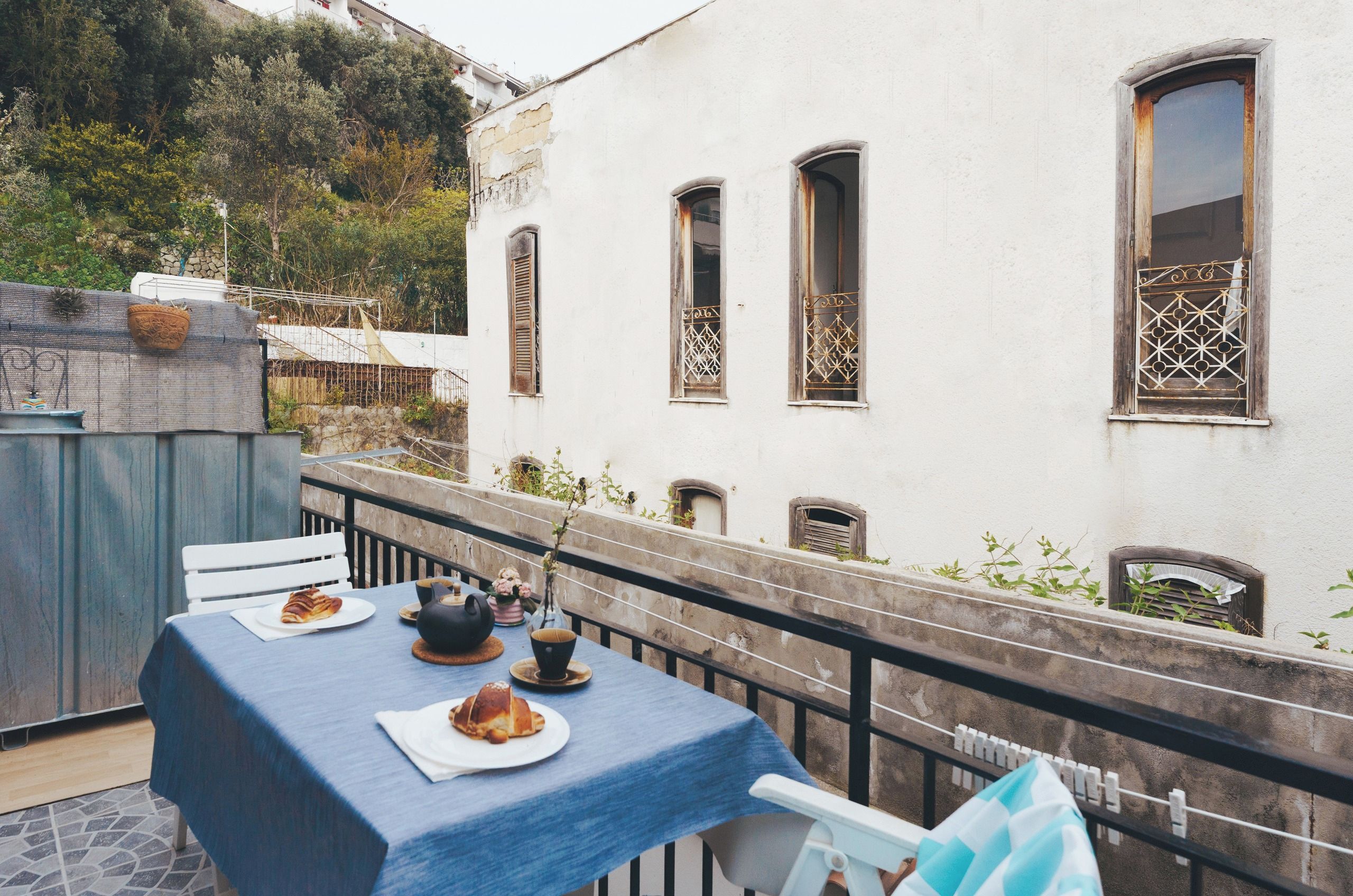 Una terrazza con un tavolo apparecchiato per due, con un croissant e una teiera.
