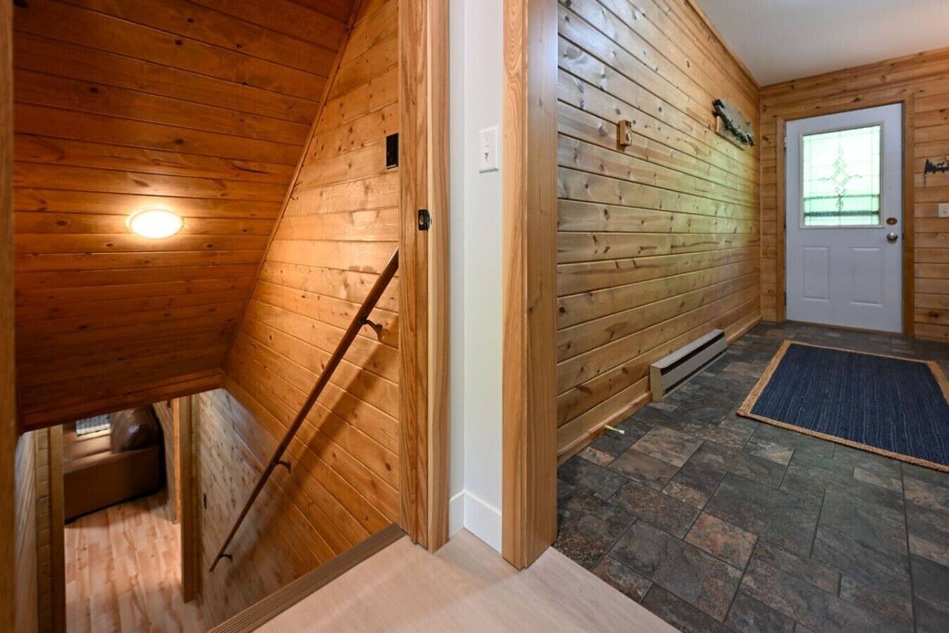 Un interno in legno con un soffitto spiovente, una porta con finestra e un pavimento in pietra.