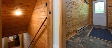 Un interno in legno con un soffitto spiovente, una porta con finestra e un pavimento in pietra.