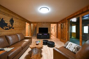 L’intérieur d’une cabane en rondins, avec un canapé, une table basse et un téléviseur.