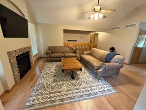 A living room with a fireplace, two sofas, a coffee table, and a patterned rug.