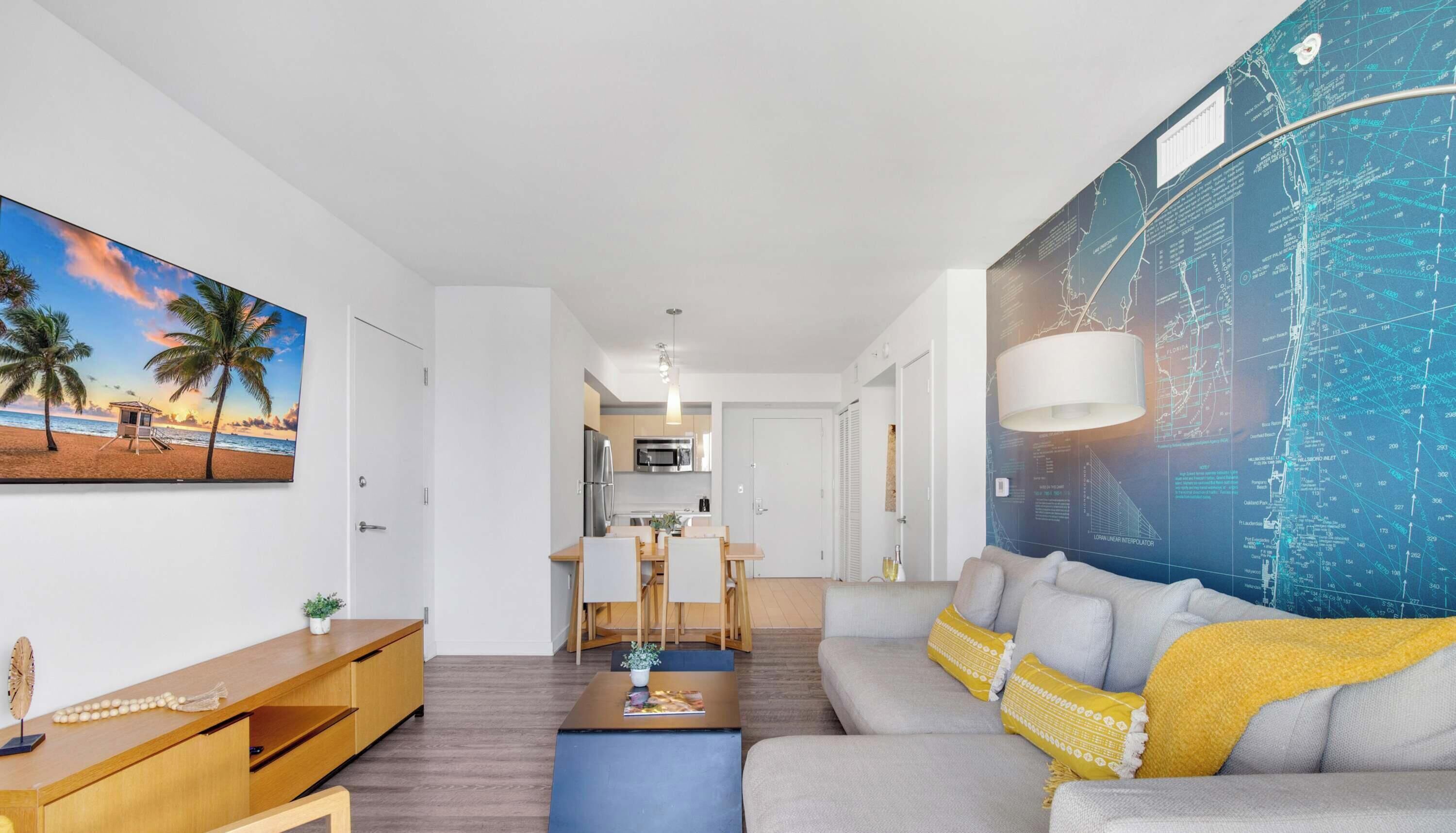 Una sala de estar moderna con un sofá, una mesa de centro y un cuadro de una escena de playa.
