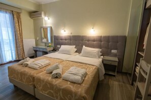 A hotel room with a large bed, a bedside table, a nightstand, a mirror, and a window with curtains. - Aklidi Hotel (Lesvos)