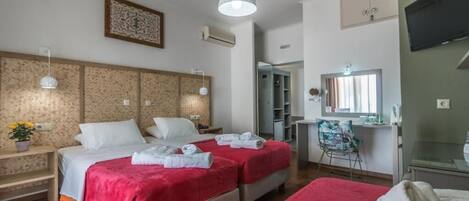 A hotel room with two beds, a TV, a desk, and a bathroom.