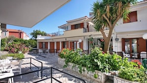 Un patio con mobiliario exterior, una palmera y un edificio con balcones.