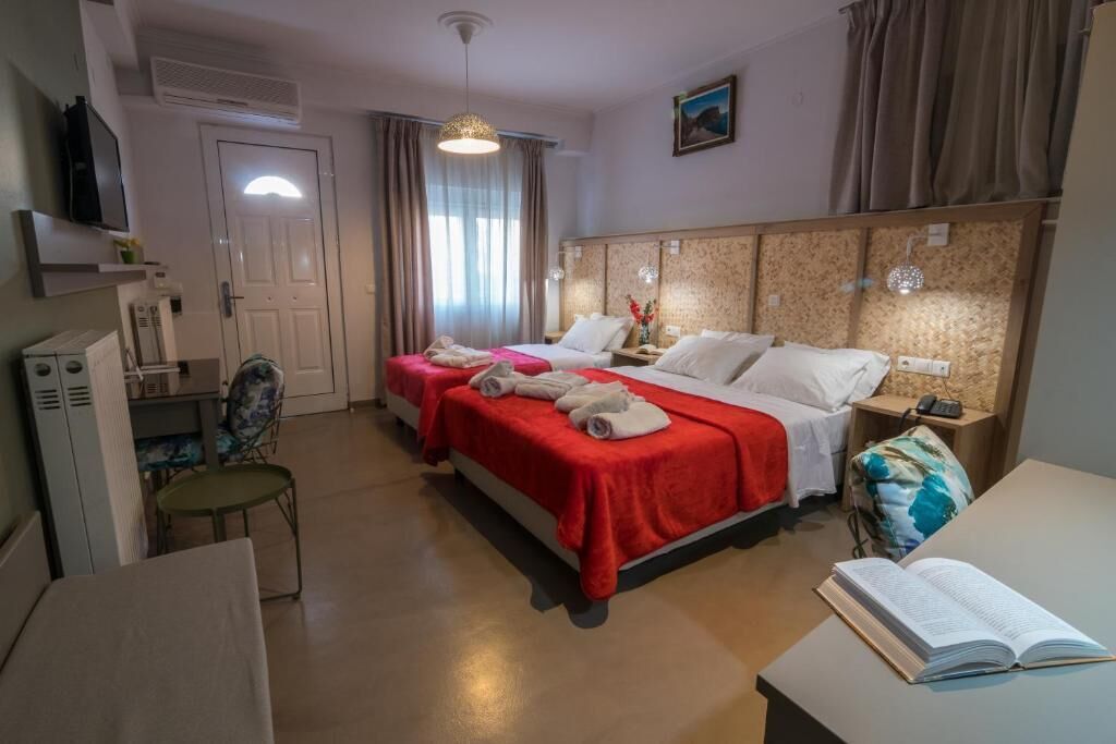 Habitación de hotel con dos camas, un escritorio, una silla, un televisor y una ventana con cortinas.