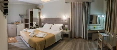 Una habitación de hotel con cama, mesita de noche, escritorio y espejo.