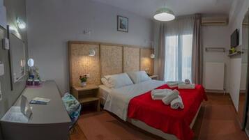 A hotel room with a bed, bedside table, lamp, and a desk with a chair.