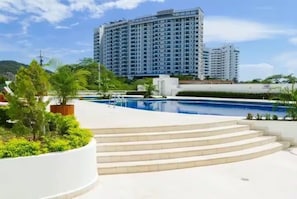 A swimming pool area with steps leading to a building, surrounded by greenery. - Oceanfront Penthouse Near Rodadero Beach (Gaira)