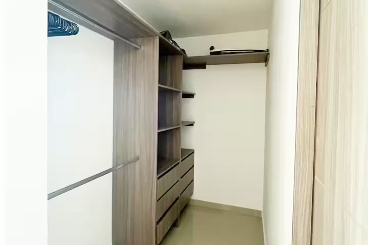 A narrow hallway with a wooden wardrobe and a shelf unit.