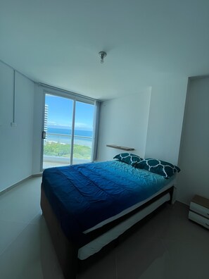 A bedroom with a bed, a window, and a view of the ocean. - Oceanfront Penthouse Near Rodadero Beach (Gaira)