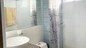 Ein Badezimmer mit einem weißen Waschbecken, einer Toilette und einer Duschkabine mit Stadtansicht-Motiv.