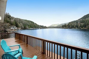 A wooden deck with chairs overlooking a calm lake, surrounded by forested hills. - Secluded 1BR Lakefront - Dock - Deck (Port Angeles)