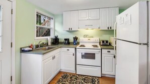 A compact kitchen with white cabinets, a stove, a sink, and a refrigerator. - Secluded 1BR Lakefront - Dock - Deck (Port Angeles)
