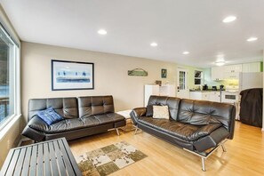 A modern living room with two leather sofas, a coffee table, and a kitchen in the background. - Secluded 1BR Lakefront - Dock - Deck (Port Angeles)
