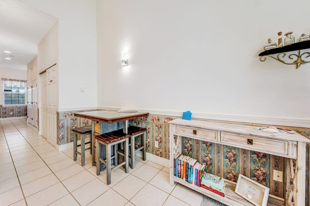 A kitchen with a dining table and chairs, a bookshelf, and a decorative wall shelf.