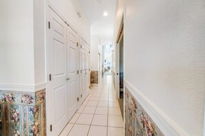 Un couloir avec des portes blanches et des carreaux muraux à motifs.