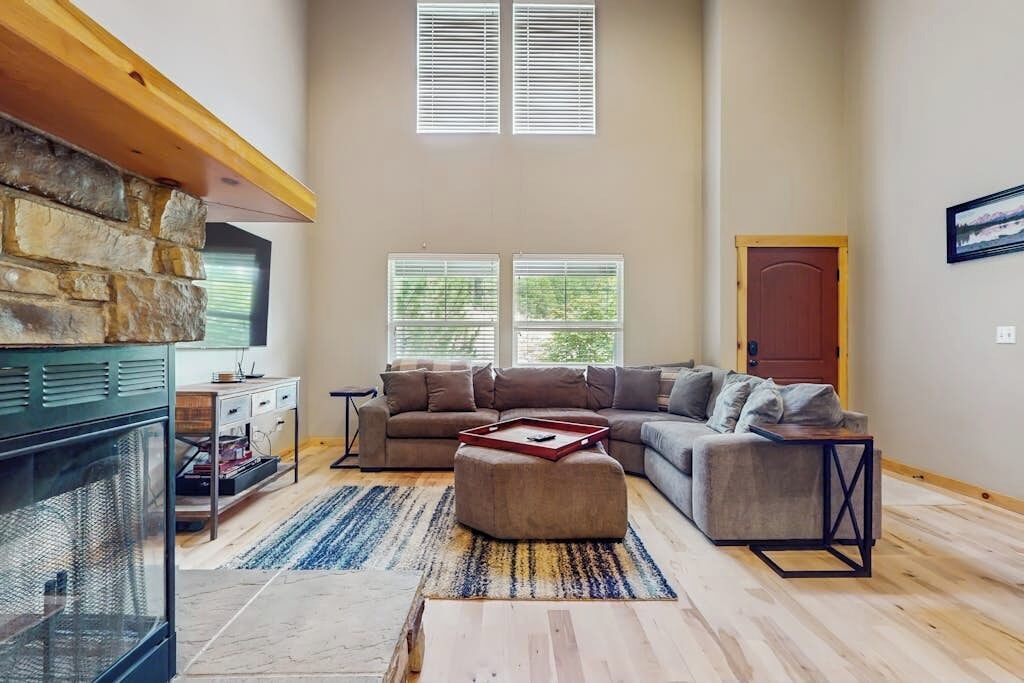 Amplia sala de estar con chimenea de piedra, sofá modular y una mesa de centro.