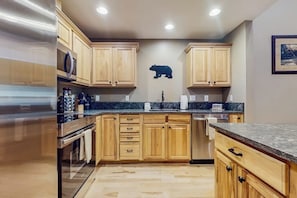 A kitchen with wooden cabinets, a stainless steel refrigerator, and a microwave. - 2 BR Townhome at the Villages at Roslyn Ridge (Ronald)