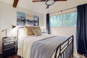A bedroom with a bed, a nightstand, a lamp, a ceiling fan, and a window with curtains. - 1BR cabin with sound views, scenic deck, & grill (Gig Harbor)