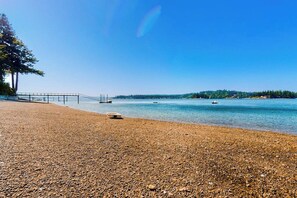 A pebbled beach with a clear sky, calm water, and a distant tree line. - 1BR cabin with sound views, scenic deck, & grill (Gig Harbor)