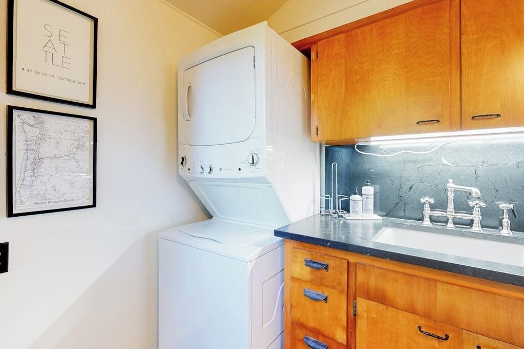 A compact kitchen with wooden cabinets, a white washing machine, and a sink with a faucet.