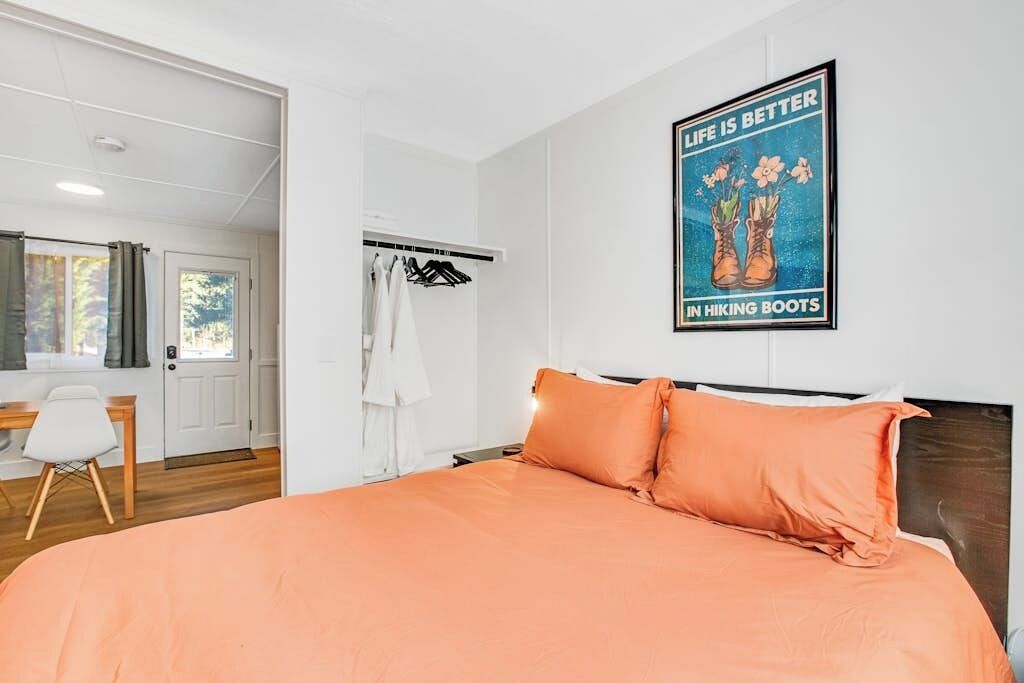 A bedroom with a bed, a wardrobe, a desk, and a poster on the wall.