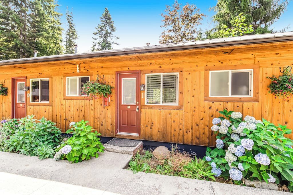 A wooden cabin with a front door, windows, and a small porch area.