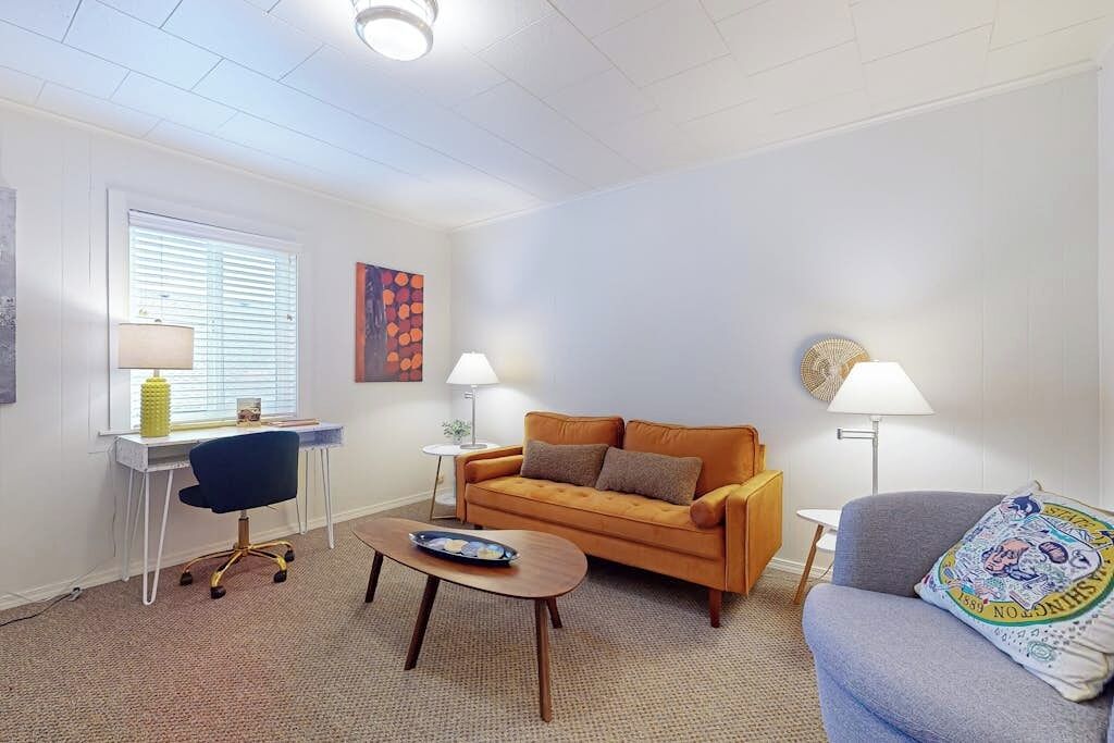 Un salon comprenant un canapé, un fauteuil, une table basse et un bureau avec une lampe.