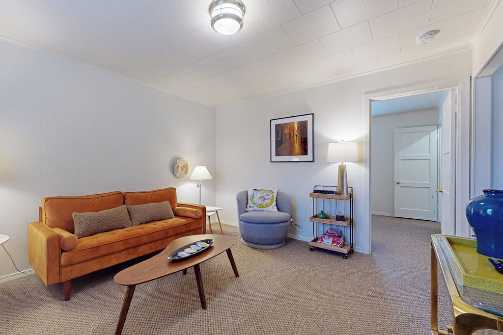 A living room with a sofa, armchair, coffee table, lamp, and a bookshelf.