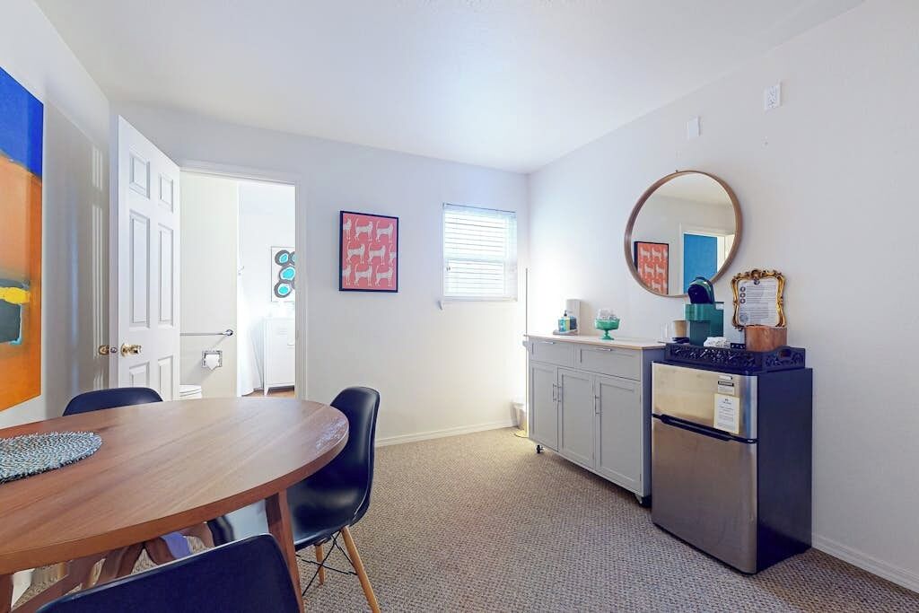 A compact kitchen with a refrigerator, a sink, and a dining area with a table and chairs.
