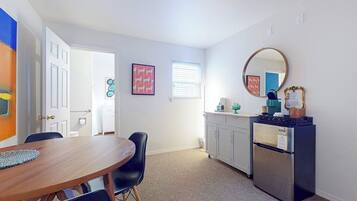 A compact kitchen with a refrigerator, a sink, and a dining area with a table and chairs.