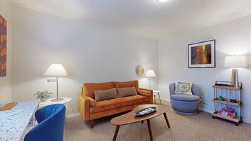 Ein Wohnzimmer mit einer Couch, einem Couchtisch, einer Lampe, einem Sessel und einem Bücherregal.