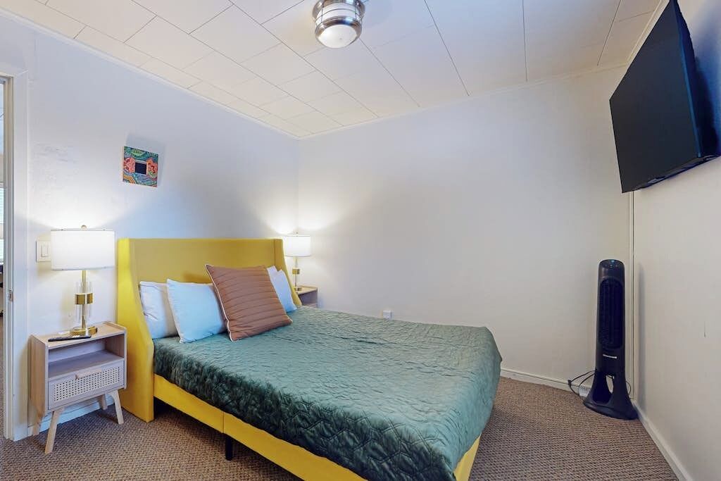Een hotelkamer met een bed, bedlampen, een flatscreen televisie en een elektrische kachel.
