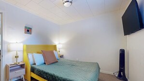 A hotel room with a bed, bedside lamps, a flat-screen TV, and a standing heater. - 1BR Hotel Room right in Downtown Port Townsend (Port Townsend)