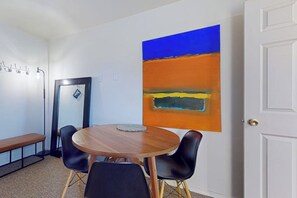 A room with a round wooden table, black chairs, a bench, and a large abstract painting on the wall. - 1BR Hotel Room right in Downtown Port Townsend (Port Townsend)
