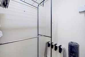 Een kamer met een metalen rek, een witte muur en een zwart object aan de rechterkant.