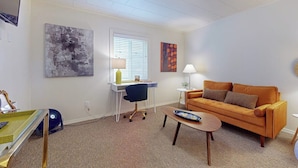 A living room with a sofa, a desk with a chair, a lamp, and artwork on the walls. - 1BR Hotel Room right in Downtown Port Townsend (Port Townsend)