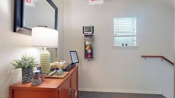 A hallway with an exit sign, a clock, a fire extinguisher, and a window.