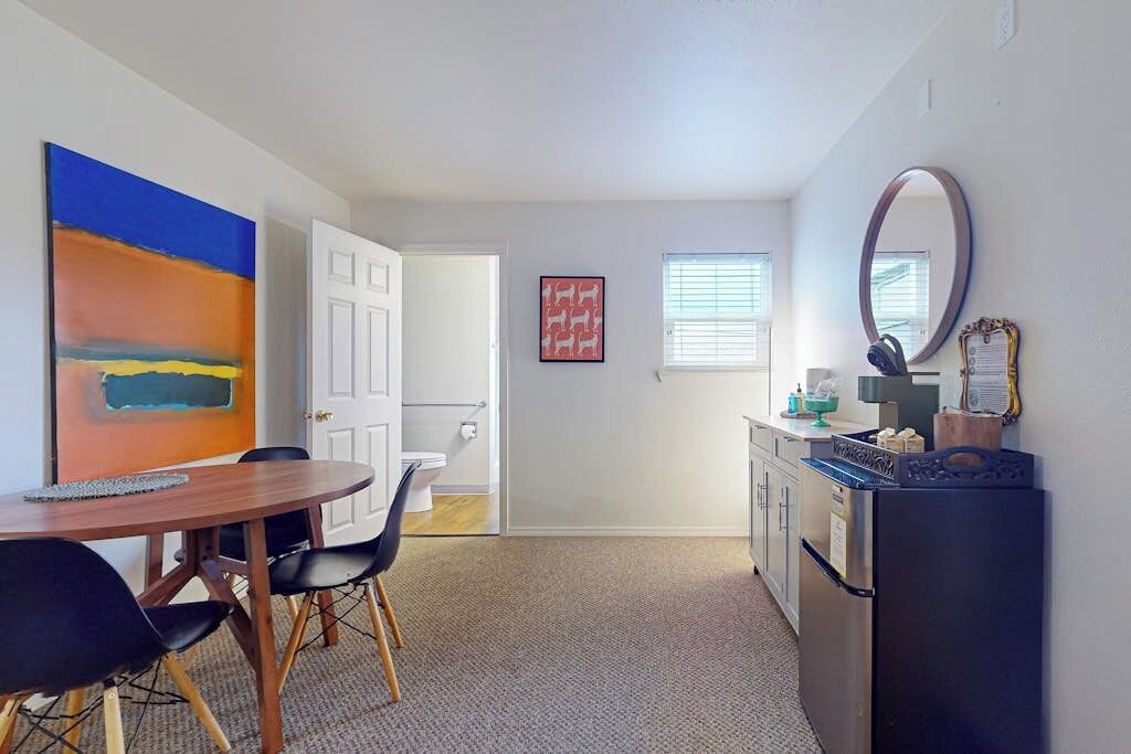 A compact living space with a dining area, kitchenette, and a door leading to another room.