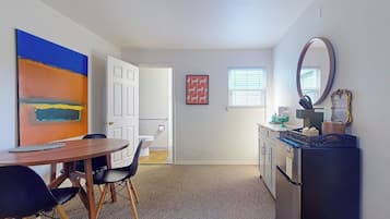A compact living space with a dining area, kitchenette, and a door leading to another room.