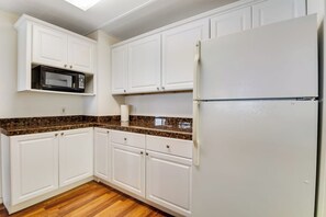 A kitchen with white cabinets, a microwave, a refrigerator, and a granite countertop. - 2BR Oceanview Birch Bay Dog Friendly - Patio (Blaine)