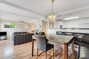 A modern kitchen with a central island, a dining area with a table and chairs, and a living area with a sofa and television. - 2BR Oceanview Birch Bay Dog Friendly - Patio (Blaine)