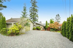 A residential property with a gravel driveway, a detached garage, and a well-maintained garden with various shrubs and trees. - 2BR Oceanview Birch Bay Dog Friendly - Patio (Blaine)