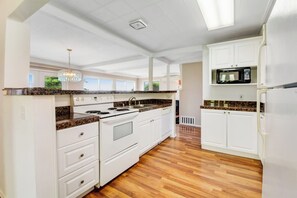 A kitchen with white cabinets, a granite countertop, a stove, and a microwave. - 2BR Oceanview Birch Bay Dog Friendly - Patio (Blaine)